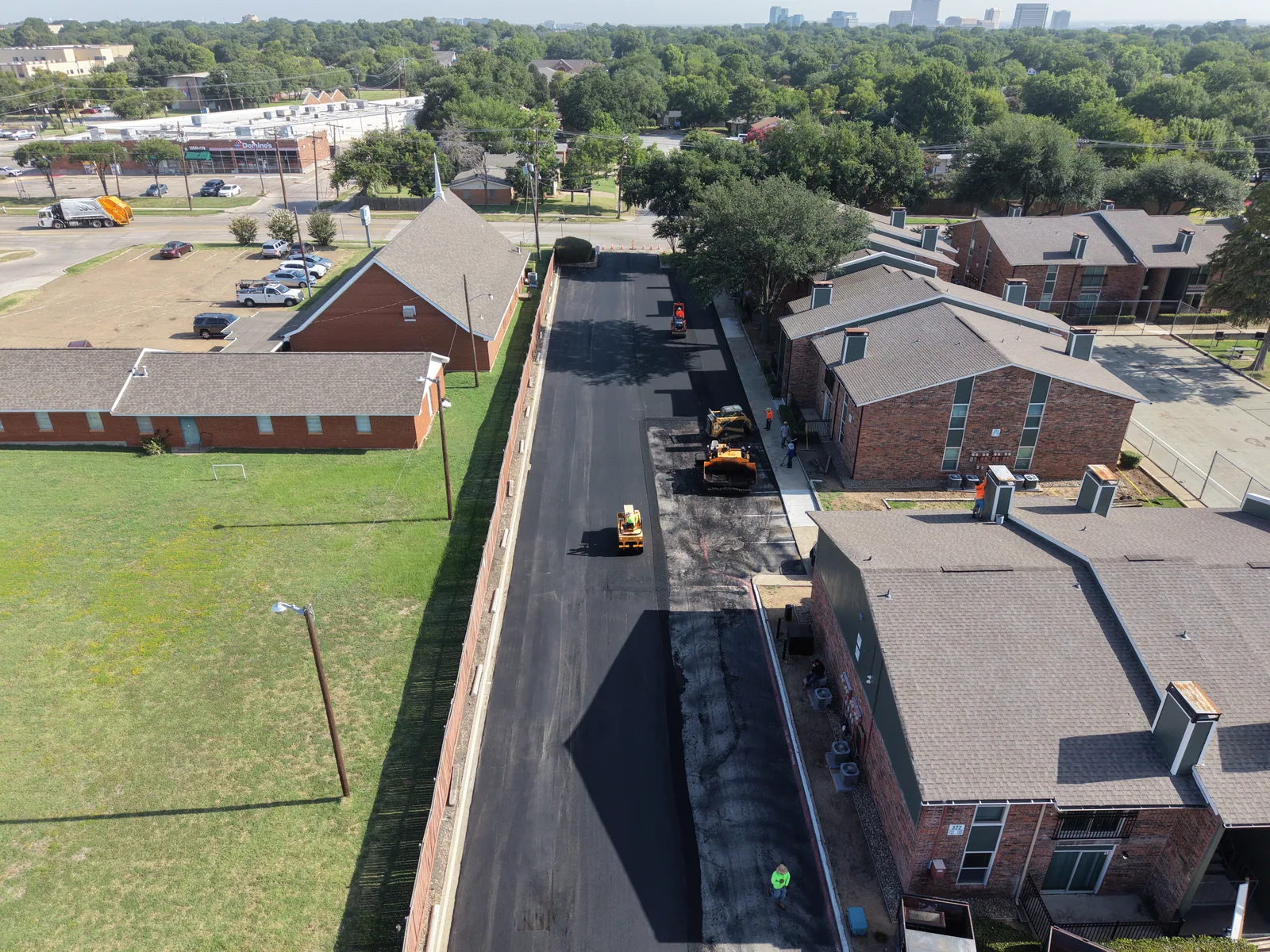 Aerial view of asphalt paving equipment working along a commercial drive